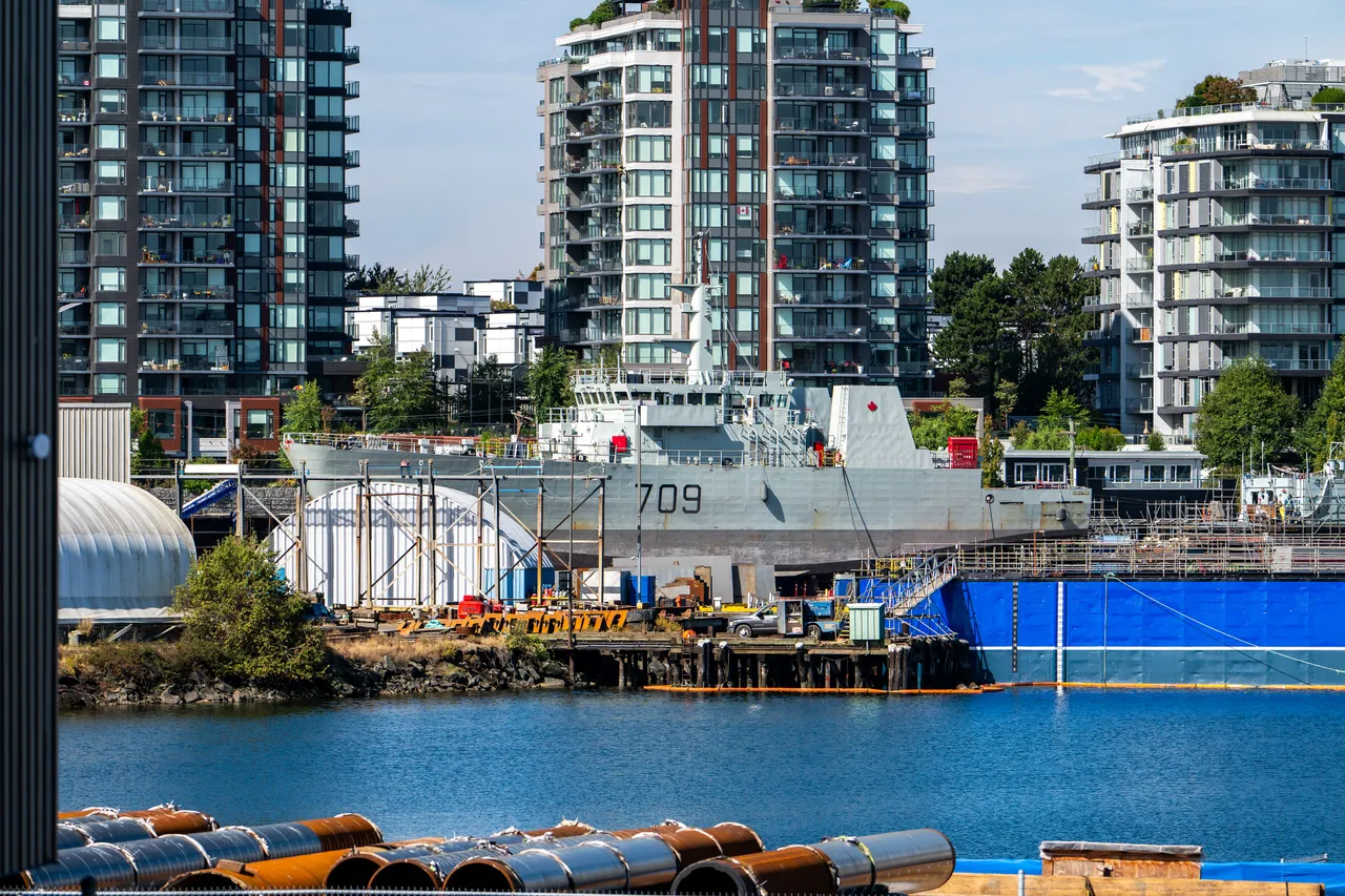 Naval Vessel Docked Beneath Modern Waterfront Condos on a Sunny Harbour