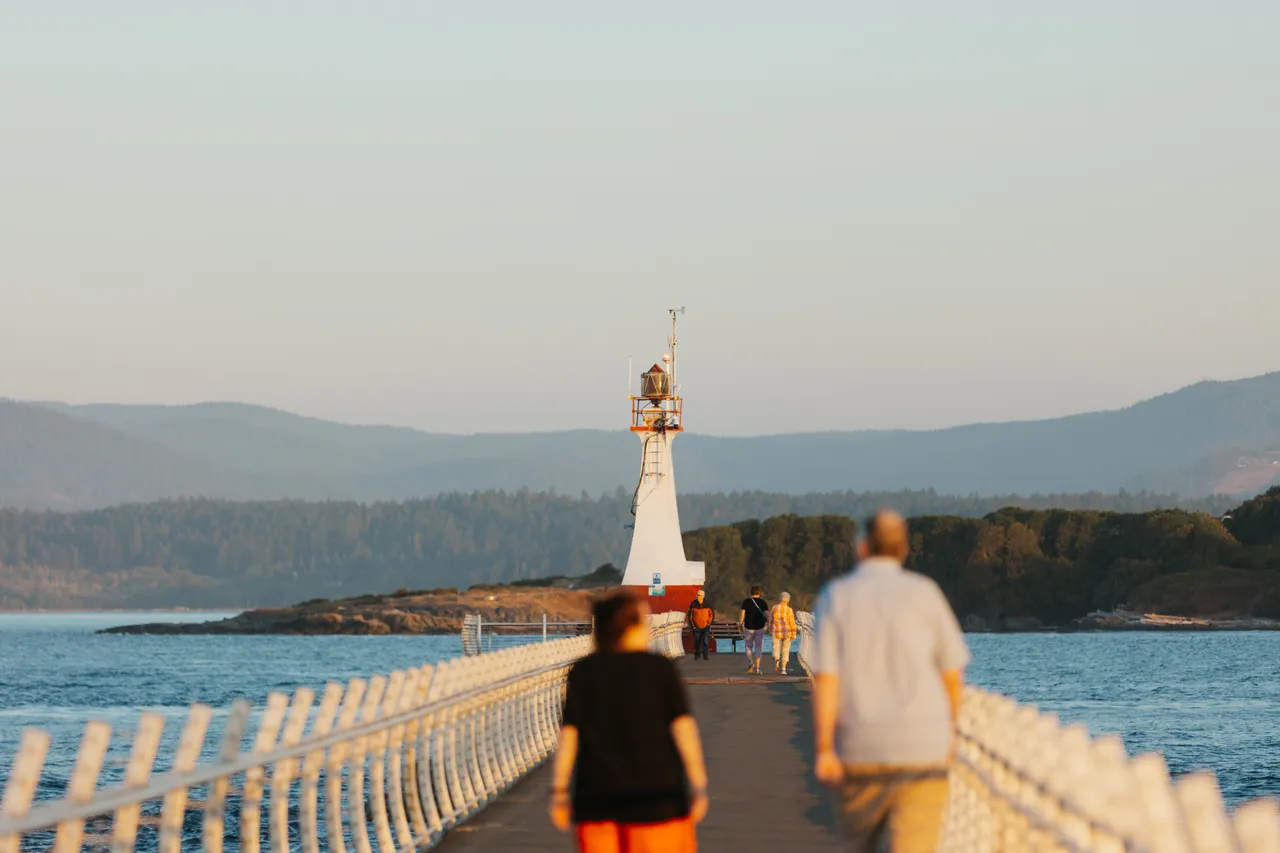 Evening stroll along a coastal pier toward the lighthouse