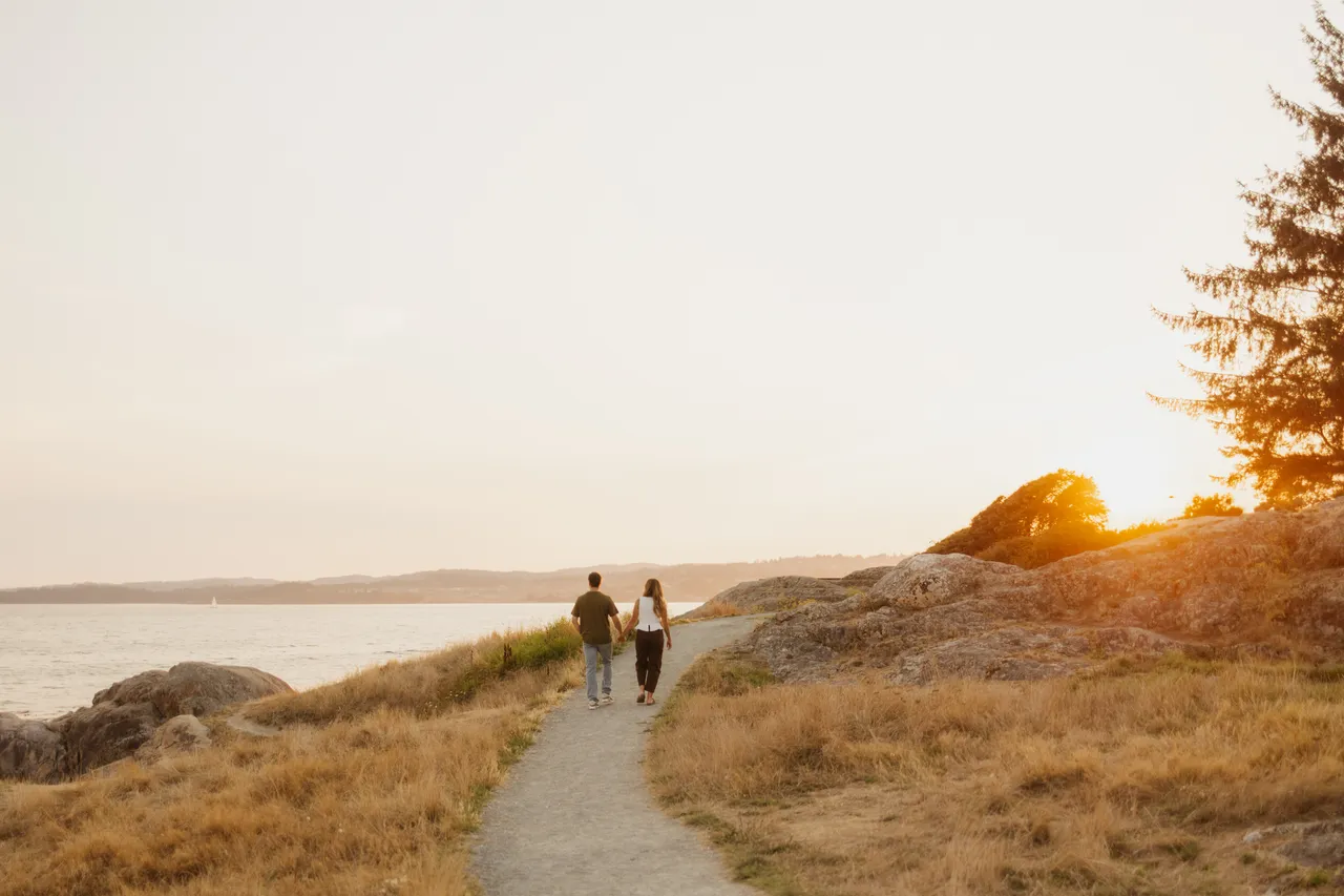 Couple walking along coastal path at golden sunset