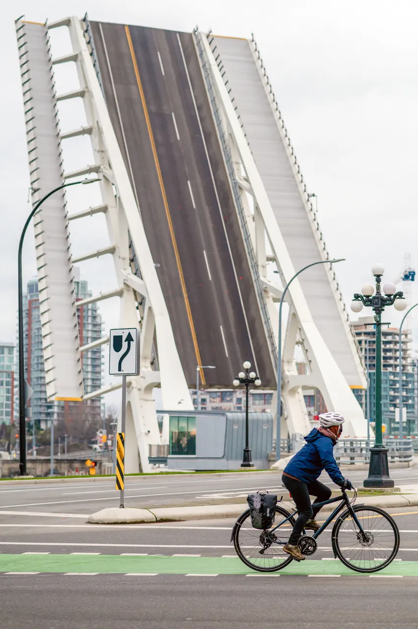 Man cycling in front of upwards drawbridge - Victoria